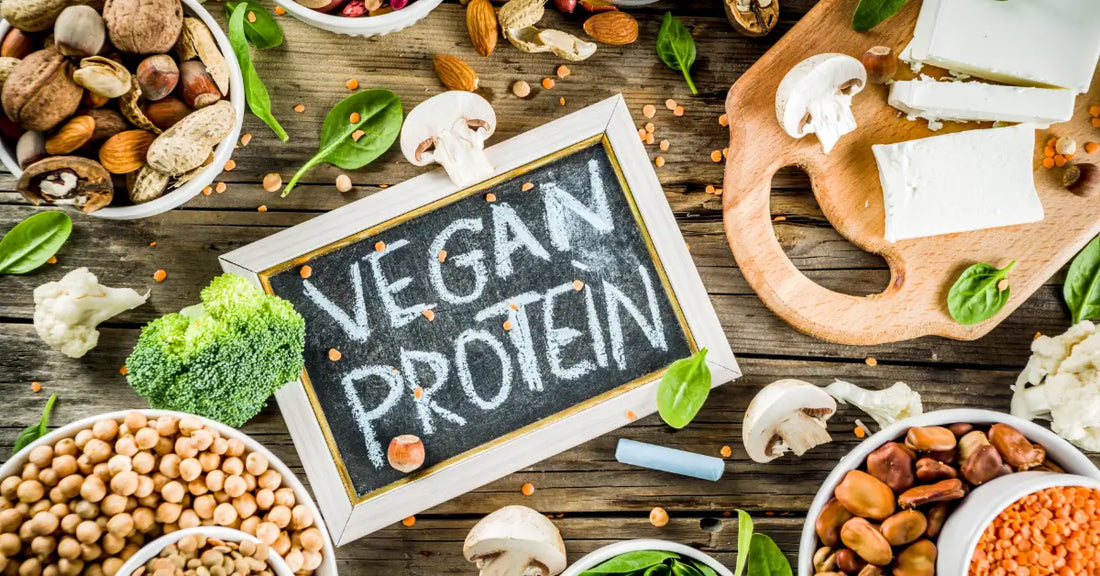 Assortment of vegan protein sources including nuts, seeds, and vegetables with a chalkboard sign reading 'Vegan Protein' illustrating how to get protein as a vegan.