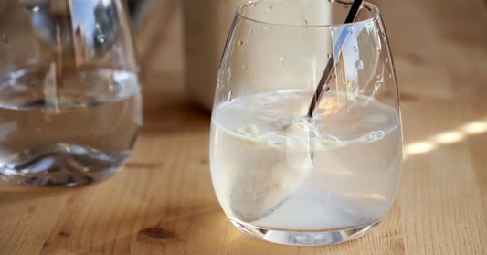 Clear glass with a spoon stirring a protein powder