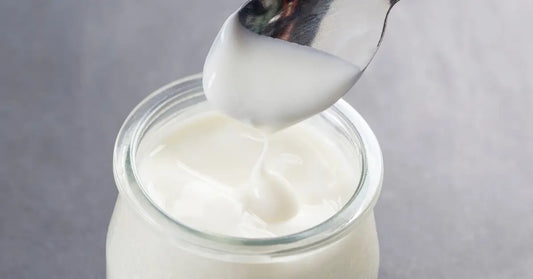 1 Close-up of a spoon dipping into a jar of yogurt, illustrating how to add protein powder to yogurt.