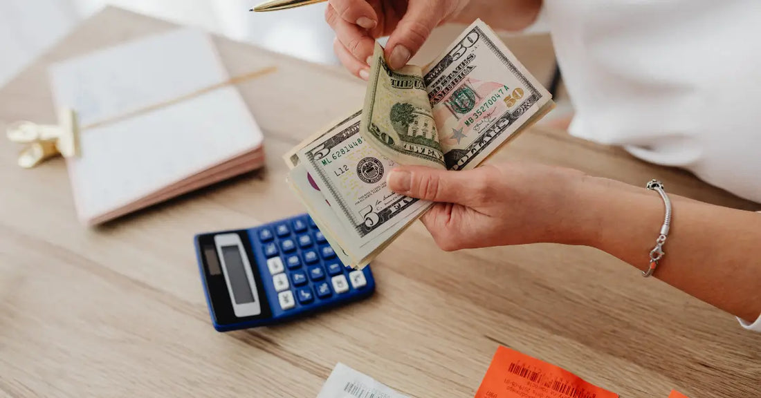 Person counting money with a calculator and notepad nearby, illustrating budgeting and why is protein powder so expensive.